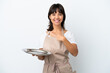 © luismolinero - Young waitress with tray isolated on white background pointing to the side to present a product