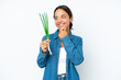 © luismolinero - Young hispanic woman holding chive isolated on white background looking to the side and smiling