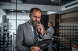 © Migma_Agency - Mature businessman contemplating a tablet in modern office