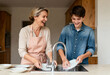 © Anna - Happy mother and teenage son washing dishes together in the kitchen. Cheerful family bonding while doing household chores