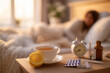 © Oleh - An alarm clock, cup of tea with lemon, medicine bottle, pills, and thermometer on a bedside table
