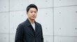 © Yesi - Professional portrait of an Asian man in casual attire standing against a modern minimalist wall