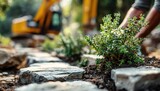 Landscape designer places shrubs, plants. Construction site with stones path, excavator blurred background. Gardener hands work with soil ground in garden. Design, nature, landscaping concept.
