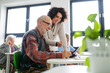 © Halfpoint - Senior man learning digital skills with tutor support in community center.