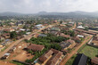 © AmazingAerialAgency - Aerial view of the rooftops nestled among trees, with distant mountains under a hazy sky, Ife, Osun, Nigeria.
