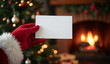 © Rhony - Santa hand holding a blank card mockup on christmas tree and fireplace background