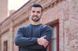 © Cristina Garcia - Confident young man smiling, arms crossed outdoors