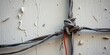 © Cherrin - Tangled wires tied against a textured wall with peeling paint.