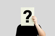 © Midnight Studio - Unidentified man holds of paper with a question mark covering his face, standing on white background. Concept of doubt, and frequently asked questions.