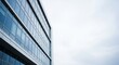 © An - A modern glass building with a cloudy sky in the background.