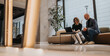 © qunica.com - Two professionals sit on a contemporary lounge with a laptop, collaborating in a bright modern lobby, conveying teamwork, planning, and professional collaboration.
