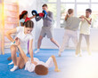 © JackF - Focused teenage girl learning effective self defence techniques in sparring with boy, practicing painful armlock on opponent lying face down on floor in gym