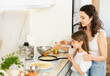 © JackF - Happy mother and her preteen daughter frying pancakes on stove in the kitchen