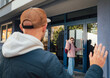 © Soloviova Liudmyla - Smiling child in warm clothes waves while entering modern school building, creating cheerful morning mood. Dad stands nearby returning gesture highlighting supportive family routine.