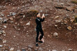 © Vladislav - Young woman with dark hair, wearing black athletic clothing, is taking a selfie on rocky terrain, capturing a moment of adventure and exploration in nature