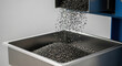 © Bakha - Efficient plastic pellet dispensing machine releasing black granules into stainless steel container in modern industrial manufacturing facility for precise material processing