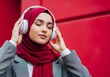 © SITI - Relaxed Muslim Woman in Red Hijab Listening to Music on Headphones | Peace, Digital Audio, and Lifestyle