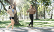 © NAMPIX - Two cheerful young Asian women enjoying a morning run together on a path in a beautiful, sunny park