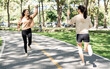 © NAMPIX - Two cheerful young Asian women giving each other a high-five while running in a sunny park