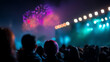 © kobkeroku - Crowd watches colorful fireworks bursting in the night sky at a lively outdoor event with vibrant lights and blurred silhouettes creating a festive atmosphere