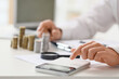 © Pixel-Shot - Businessman with stacks of coins using calculator at table in office, closeup. Tax concept