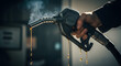 © Roy Arifin - Fuel nozzle drips gasoline, creating an image of waste and environmental concerns, A hand holds a fuel pump, dripping with golden gasoline, emphasizing resource depletion