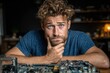© Alexei - Young man with curly hair and beard is thoughtfully examining a computer motherboard, showcasing his analytical skills and interest in technology and electronics