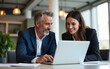 © Mason - Mature mentor man and European leader woman discussing project on laptop in office. Two diverse partners, colleagues, team of confident professional business people work together. Banner, copy space