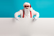 © deagreez - Santa with red suspenders beard holds blank sign against blue background creating festive humorous Christmas scene for holiday promotions