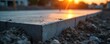 © miss irine - Concrete slab foundation close-up at construction site. Building progress shown during sunset. Groundwork and structural development. Rough unfinished surface detail. New infrastructure creation.