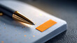 © perfectlab - Close-up of a black and gold pen resting on a white notebook with gold speckles and an orange sticky tab on a textured surface