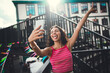 © BullRun - Young woman taking playful selfie with smartphone, arms raised and tongue out. Expressive moment of freedom, self-celebration, joy, and modern identity in digital youth culture.