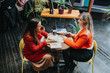 © qunica.com - Two women sit at a small round table in a cozy bookstore cafe, sharing books and conversation over coffee. A stylish, relaxed moment of friendship, reading, and ideas.