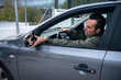 © Taras Grebinets - Focused Man Driving a Car Reaching for Side Mirror Inside a Modern Gray Vehicle