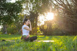© leungchopan - Woman enjoying yoga pranayama session on green grass