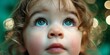 © ALL YOU NEED studio - Candid portrait close-up studio shot, a young child's face looking upwards with wide-eyed wonder, reflecting warm holiday lights in their eyes, against a smooth seamless deep forest green background