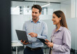 © Abdul - Two smiling colleagues collaborating on a laptop and tablet in a modern office environment discussing a project