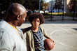 © Davor - Senior grandfather comforting child grandson on outdoor basketball court