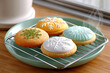 © Nataliia - Colorful round cookies with snowflake icing designs on cooling rack, freshly baked and served on mint green plate, close-up