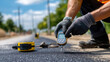 © Laura - Close-up of gloved hands measuring asphalt temperature with a tool on site, precision engineering, with copy space