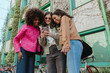 © Drobot Dean - A group of three female friends are standing and smiling while looking at a phone that one of them is showing