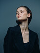 © SHOTPRIME STUDIO - Elegant woman in dark blazer looking away with a confident and thoughtful expression on a gray background.