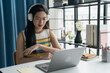 © Charlie's - Online Tutoring Asian Girl in Headphones Engaged in Online Class with Laptop education writing homework study e-learning preparing for exam