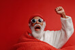 © KETE - Santa in yawning pose under red background wrapped in red blanket for cute Christmas stock photo