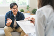 © KMPZZZ - Psychology, depression. smile asian young male, man patient mental sitting on couch, explained symptom with psychologist, psychiatrist while doctor woman taking notes at clinic. Encouraging, therapy.