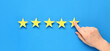 © Pixel-Shot - Female hand and five stars rating on blue background. Customer experience concept