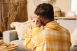 © Pixel-Shot - Young man with cute cat at home on autumn day, back view