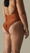 © Lustre Art Group  - Curvy woman in rust swimsuit viewed from behind with natural folds and confident stance. Concept of inclusive branding, swimwear e-commerce, authentic body-focused visuals.