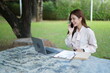 © TesLaTH - Woman working remotely at outdoor desk space.