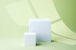 © reddish - Two minimal white cube pedestals placed side by side on pastel green background